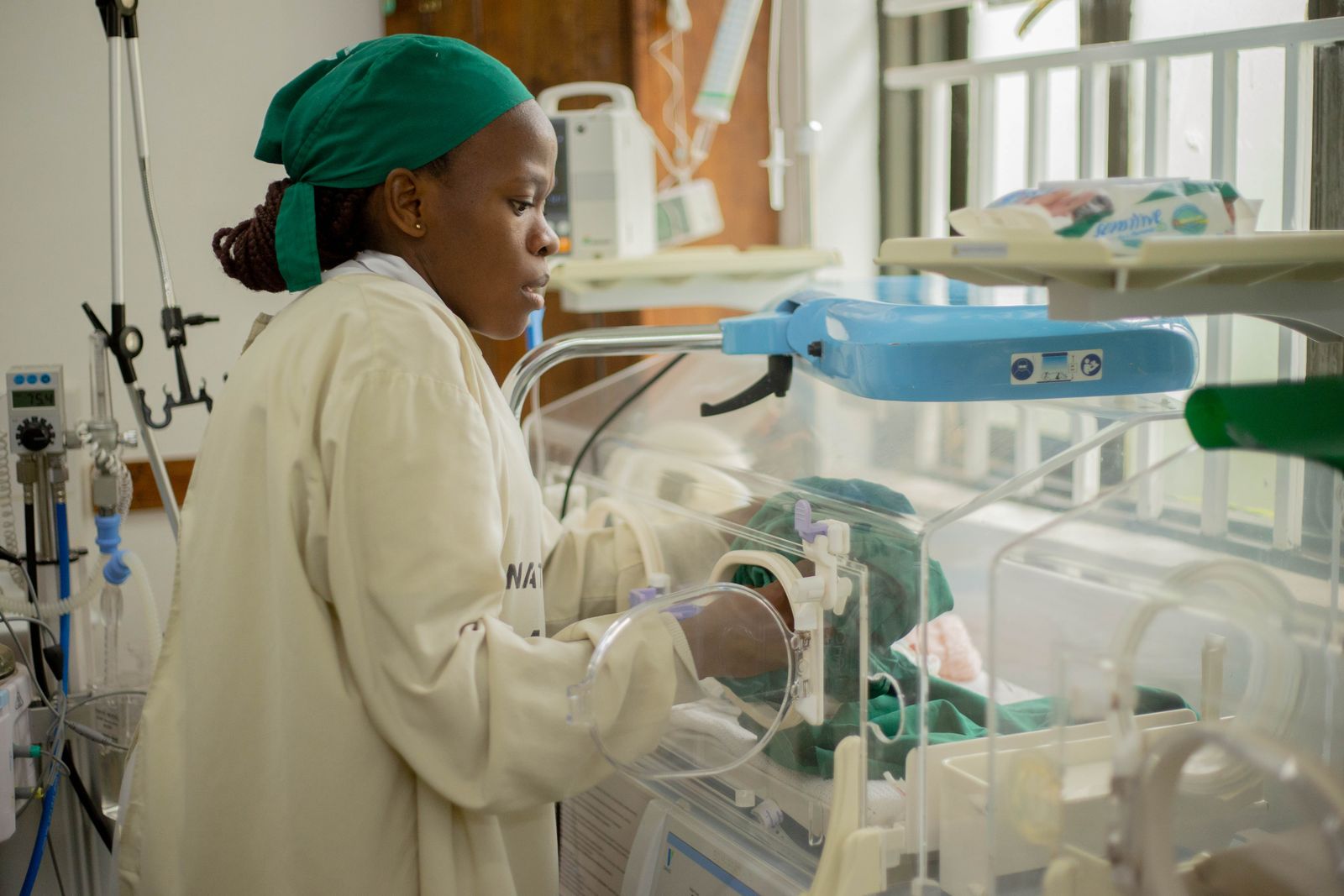 African nurse caring for a newborn in a hospital incubator